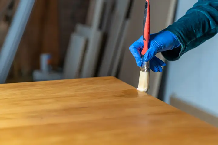Aplicación de barniz protector sobre una mesa de madera